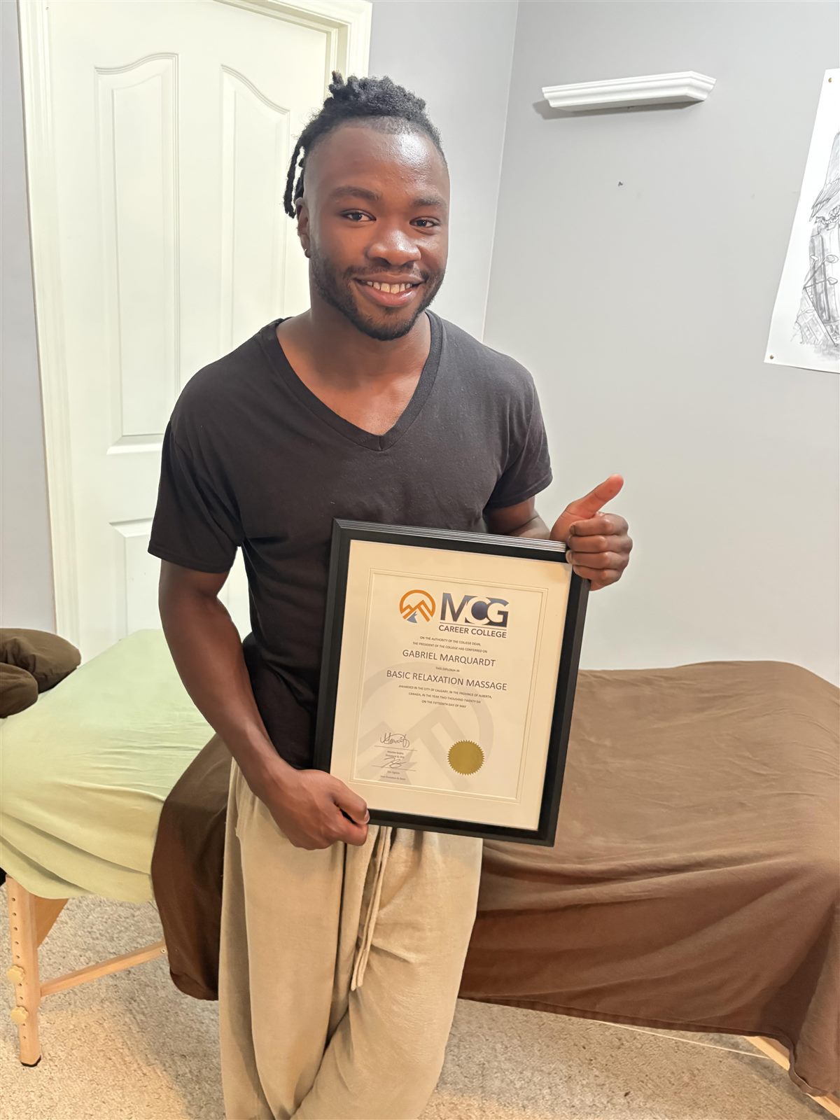 Gabriel Marquardt holding his Basic Relaxation Massage diploma from MCG Career College